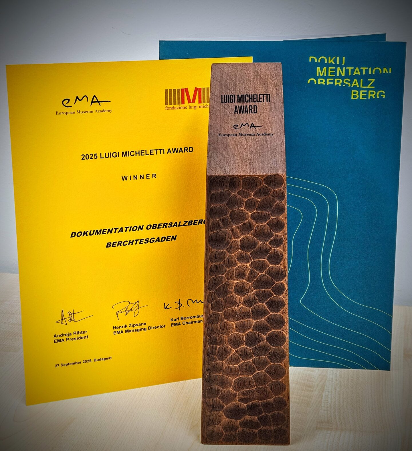Der Luigi Micheletti Award vor der Verleihungsurkunde und dem Logo der Dokumentation Obersalzberg